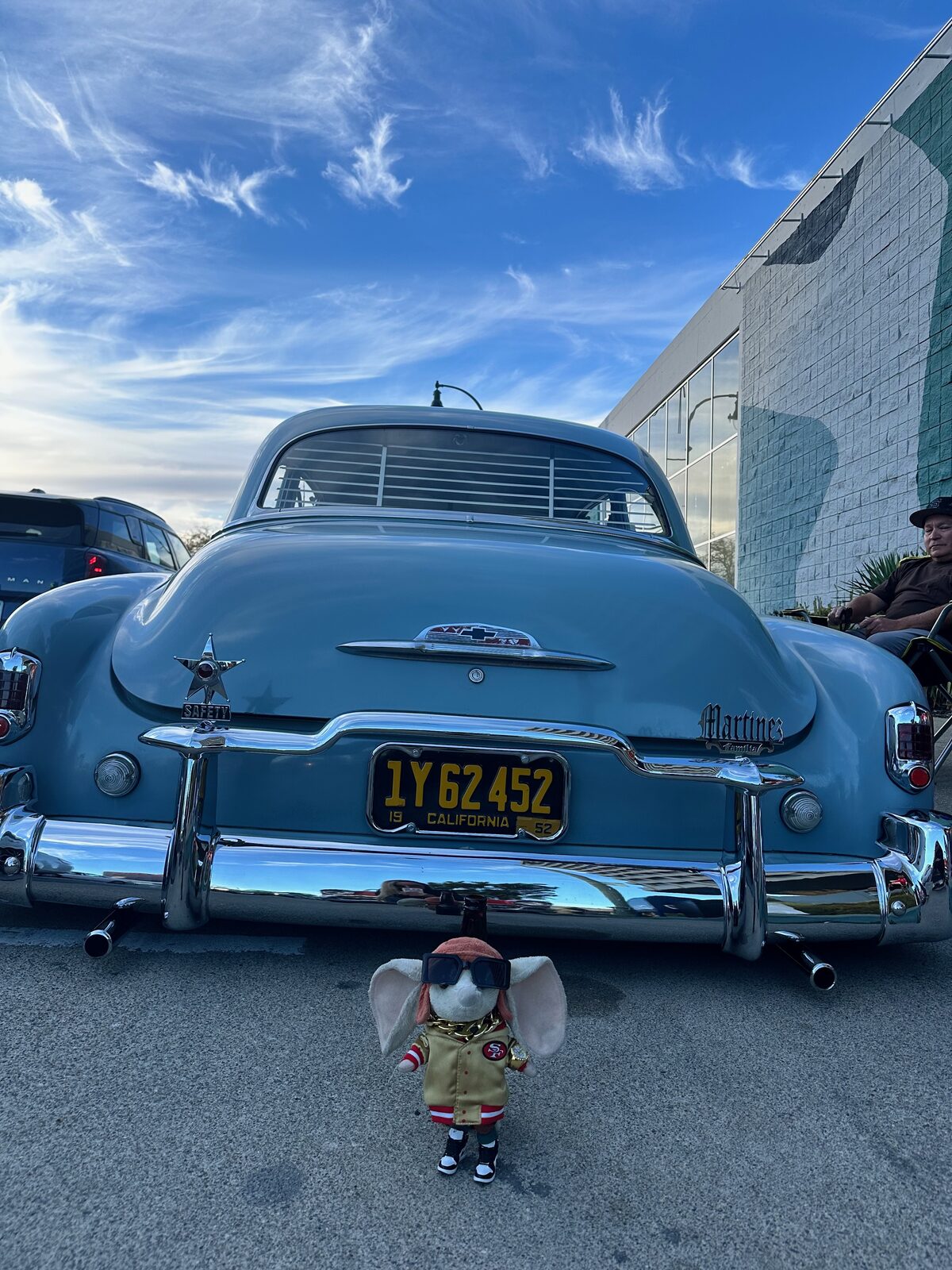 A blue 1950 Chevrolet photographed from behind under a sky streaked with clouds