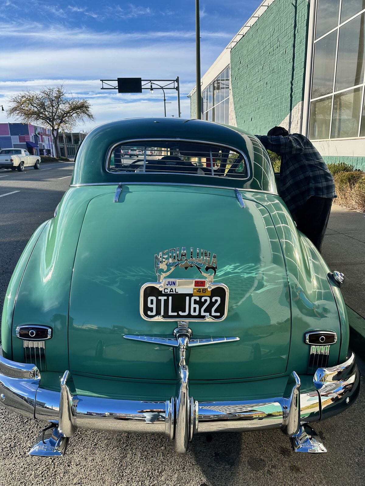 The rear of a green late-1940s Chevrolet Fleetline with polished chrome bumpers
